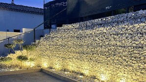 Un área ajardinada con un muro de piedra y un sendero.