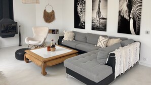 Una sala de estar moderna con un sofá seccional gris, un sillón blanco, una mesa de centro de madera y una lámpara colgante.