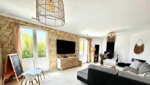 Una sala de estar moderna con un televisor grande, un sofá, una mesa de comedor y una pizarra.