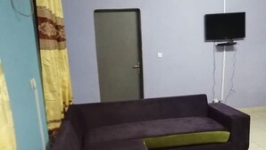 A living room with a sofa, a door, and a television mounted on the wall.