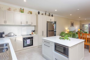 Enjoy meals in the well-lit kitchen with an oven, stainless steel refrigerator, and dining area.