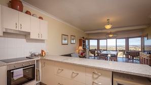 A kitchen with a large island, an oven, and a dining area with a view.