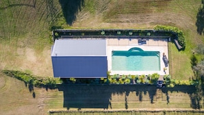 An aerial view of a property with a swimming pool, a large building, and terraced fields.