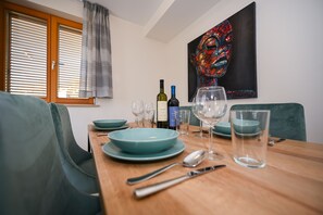 A dining area with a wooden table set for two, featuring teal plates, wine bottles, and glasses. - Casa Laurea (Dubrovnik)