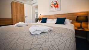 Habitación de hotel con una cama grande, un armario de madera, un cuadro en la pared y una mesita de noche con lámpara.