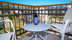 Un balcón con una mesa y dos sillas, una botella de vino y dos copas de vino.