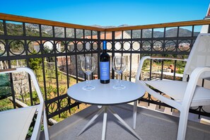 A balcony with a table and two chairs, a bottle of wine, and two wine glasses. - Casa Laurea (Dubrovnik)