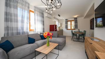 A modern living room with a grey sofa, a wooden coffee table, and a vase of flowers.