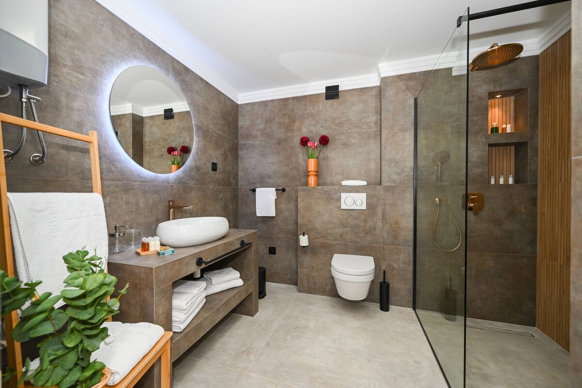 A modern bathroom with a glass-enclosed shower, a large mirror, and a vanity with a sink and towel rack.