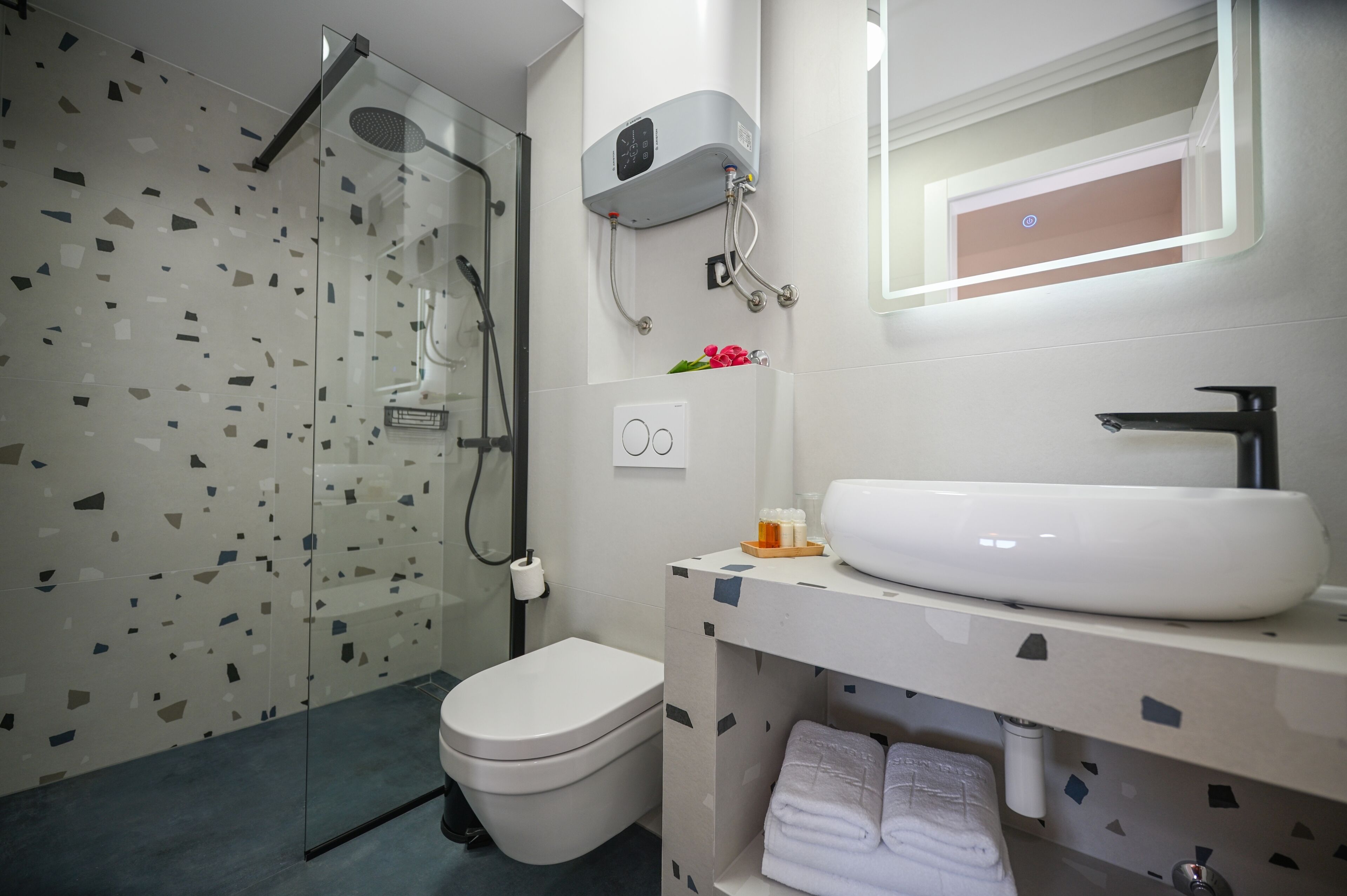 A modern bathroom with a glass shower enclosure, a toilet, a sink with a mirror, and a towel rack.