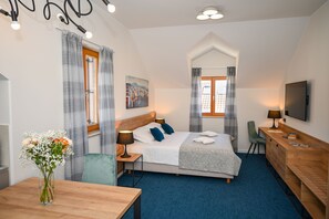 A hotel room with a bed, a desk, a chair, a TV, and a painting on the wall. - Casa Laurea (Dubrovnik)