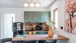 A modern kitchen with a dining table, chairs, a refrigerator, and a vase with flowers. - Casa Laurea (Dubrovnik)