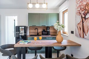 A modern kitchen with a dining table, chairs, a refrigerator, and a vase with flowers. - Casa Laurea (Dubrovnik)
