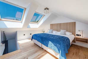 A modern bedroom with skylights, a wooden headboard, and a bedside table with a lamp. - Casa Laurea (Dubrovnik)