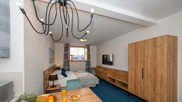 A compact hotel room with a bed, bedside table, and a breakfast table with fruit and juice. - Casa Laurea (Dubrovnik)