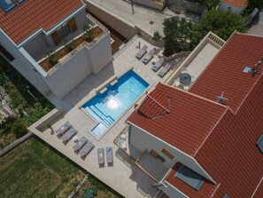 An aerial view of a property with a swimming pool, lounge chairs, and a red-tiled roof. - Casa Laurea (Dubrovnik)