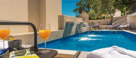 Un área junto a la piscina con una silla de descanso, un libro y un vaso de jugo de naranja.