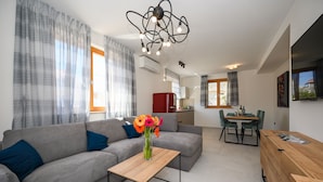 A modern living room with a grey sofa, a wooden coffee table, and a vase with flowers. - Casa Laurea (Dubrovnik)