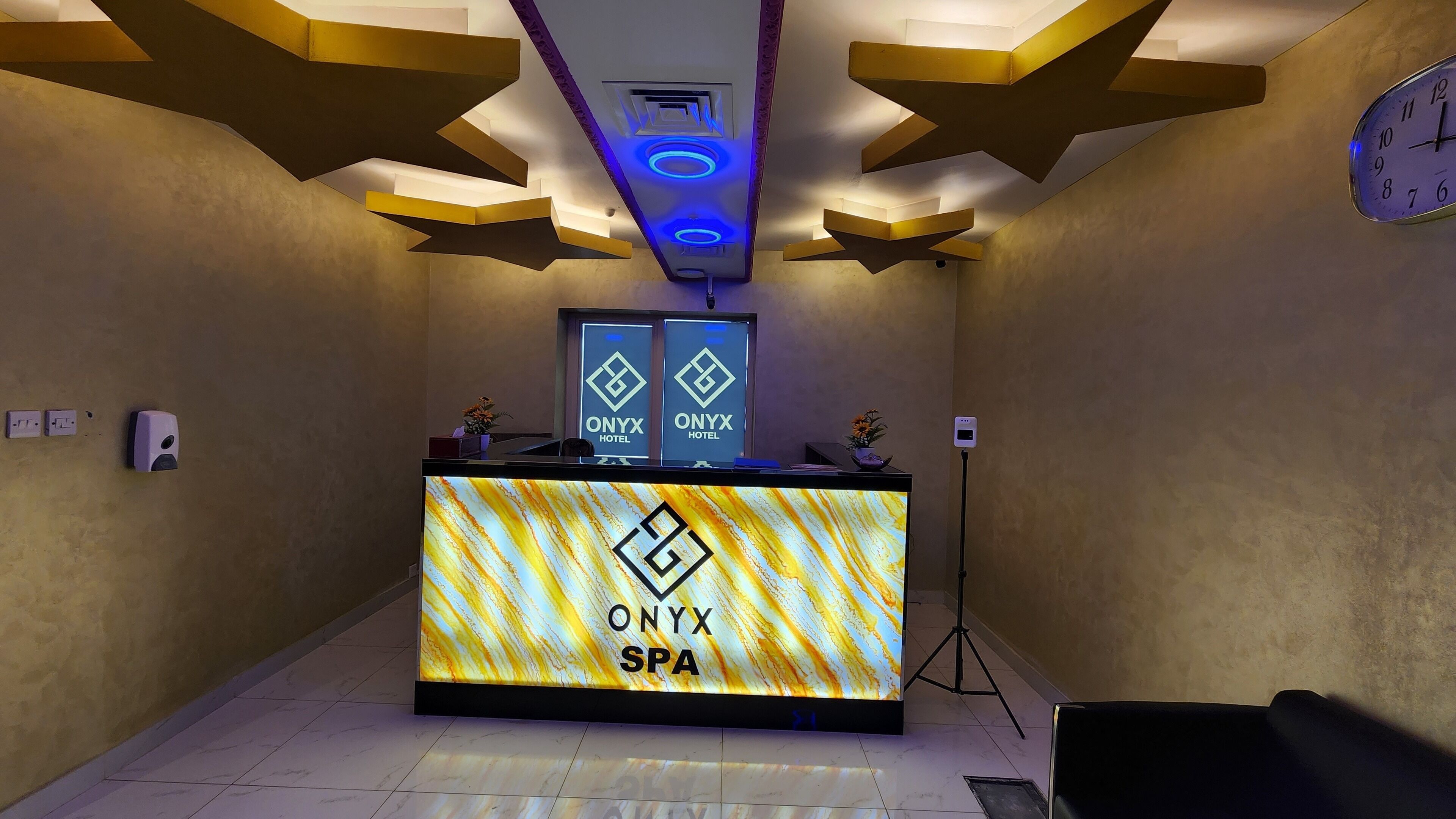 A reception area with a modern design, featuring a reception desk labeled "ONYX SPA" and two "ONYX HOTEL" signs above it.