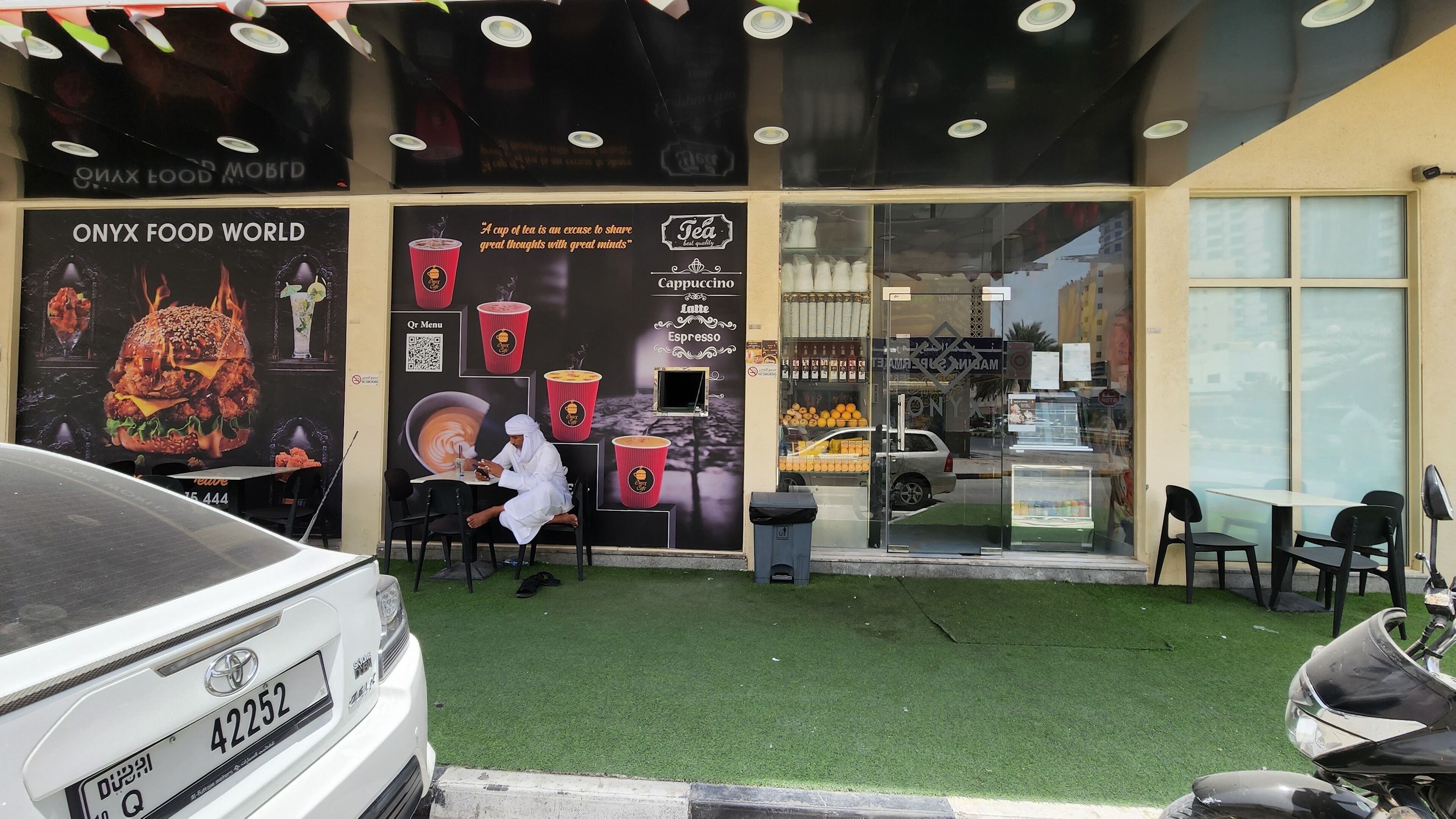 Ein Café mit Glasfront, einem QR-Code zur Bestellung und einer Tafel, die Getränke wie Cappuccino und Latte bewirbt.