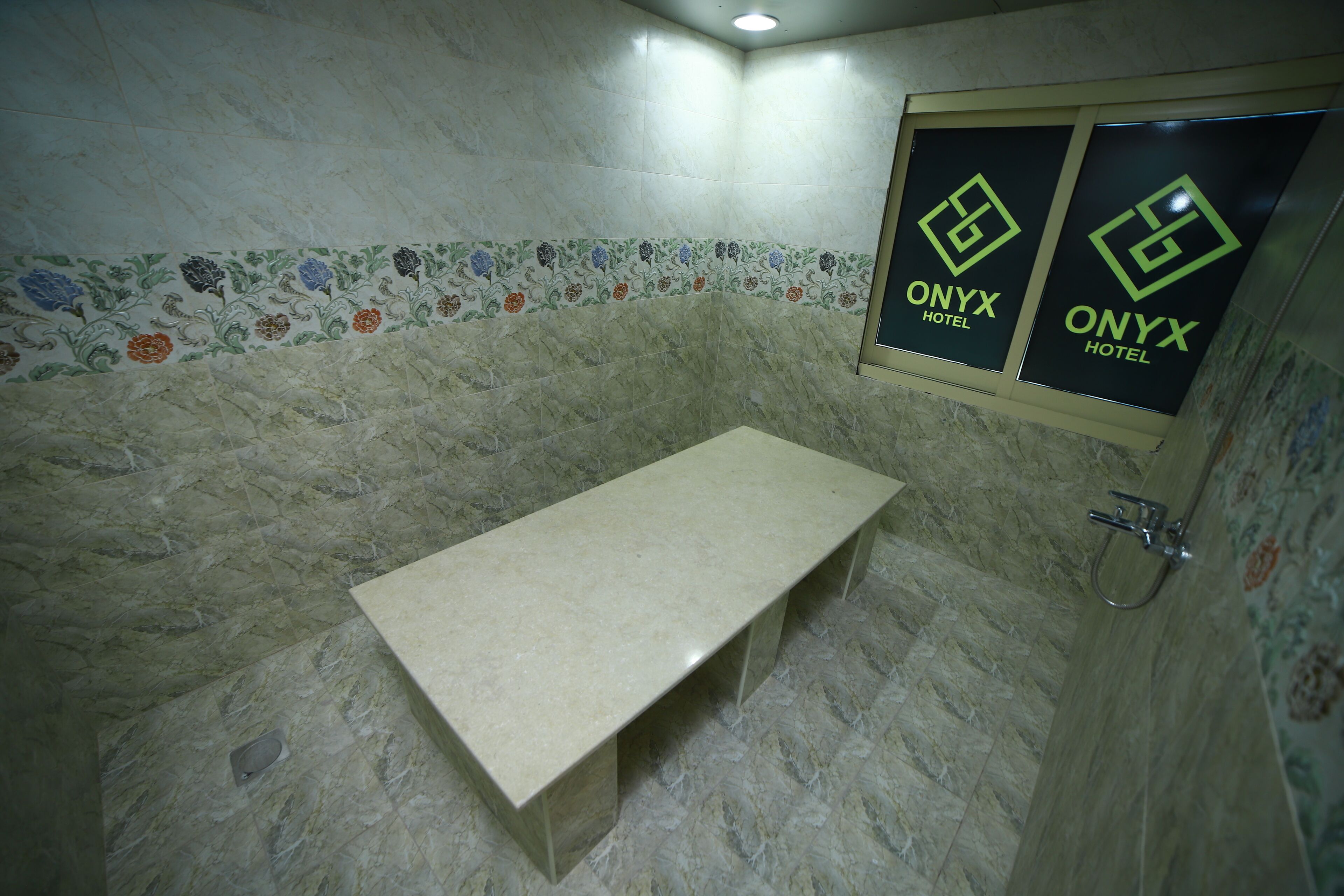 A bathroom with a marble floor, a bench, and a shower area.