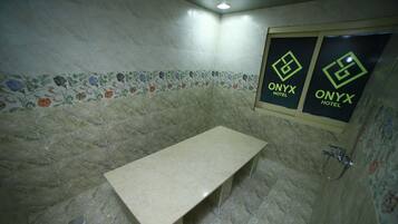 A bathroom with a marble floor, a bench, and a shower area.