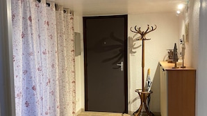 Un pasillo con piso de madera, una puerta con marco oscuro y un perchero con un adorno.
