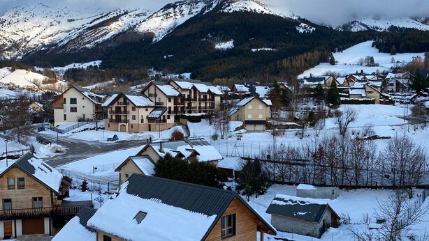 Zona residencial cubierta de nieve, con casas y una montaña al fondo.