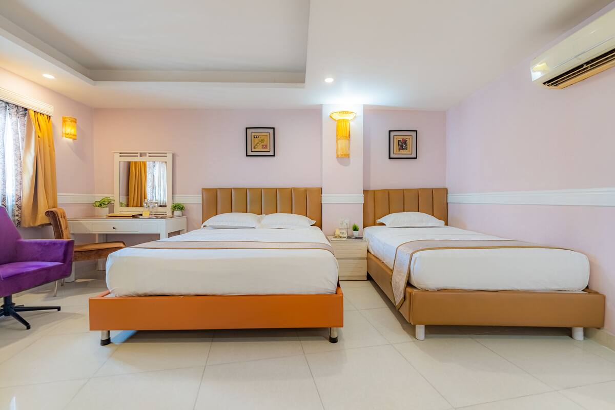 A hotel room with two beds, a desk, a chair, and a mirror.