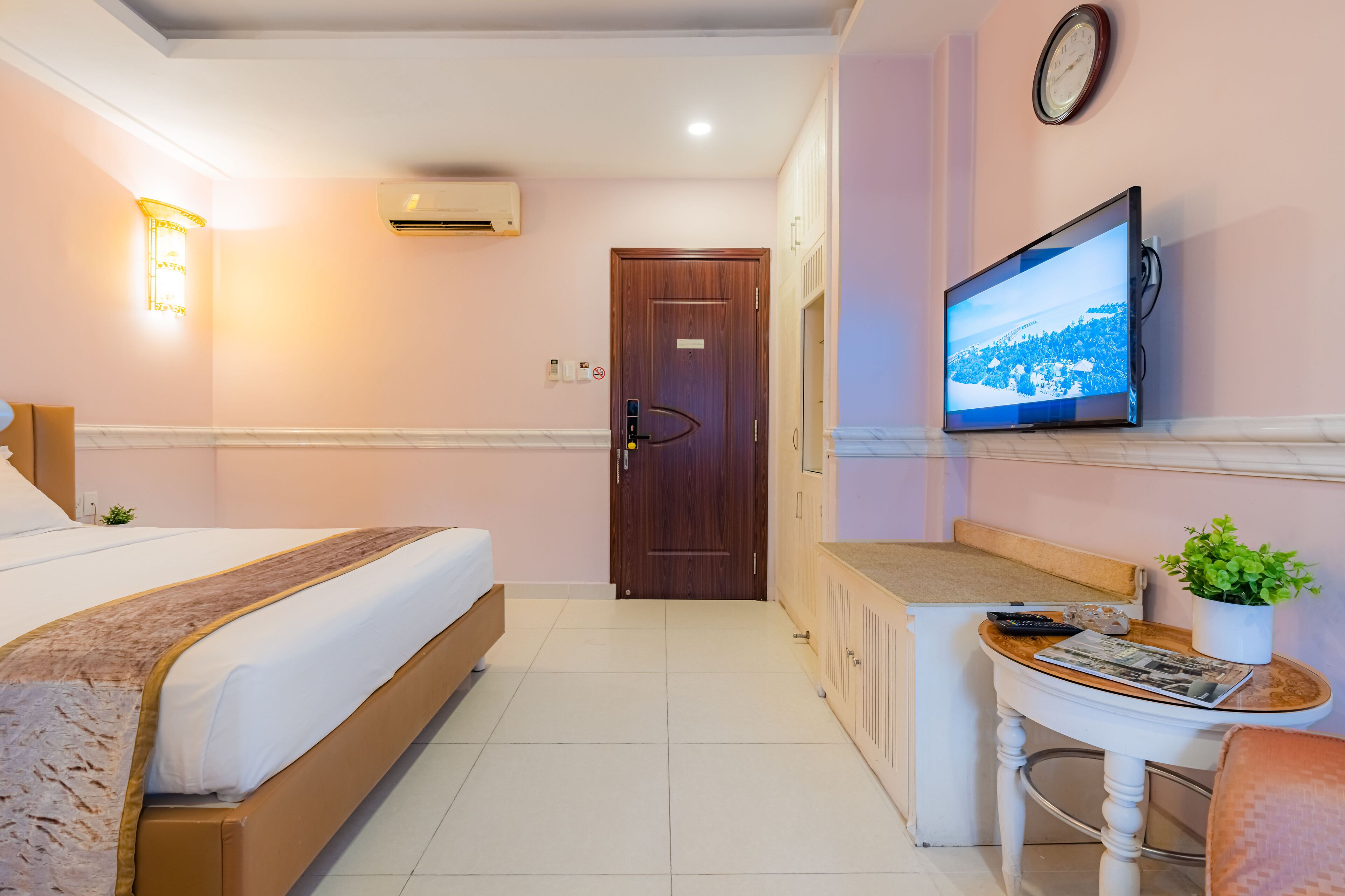 Une chambre d’hôtel avec un lit, un bureau agrémenté d’une plante, une télévision et une porte.