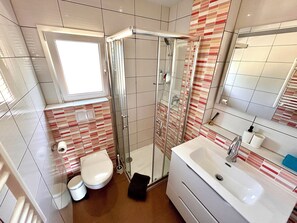 A bathroom with a glass shower enclosure, a white sink, and a toilet. - DM: By the sea, with a patio, ocean view, and garden (S'Estany d'en Mas)