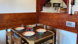 Una mesa de comedor dispuesta con platos, vasos y cubiertos, rodeada de sillas de madera.