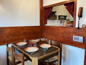 A dining table set with plates, glasses, and cutlery, surrounded by wooden chairs.