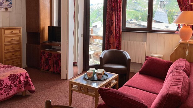 Una habitación acogedora con cama, televisión, escritorio, silla y ventana con cortinas.