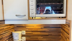 Una kitchenette compacta equipada con microondas, cafetera y estufa.
