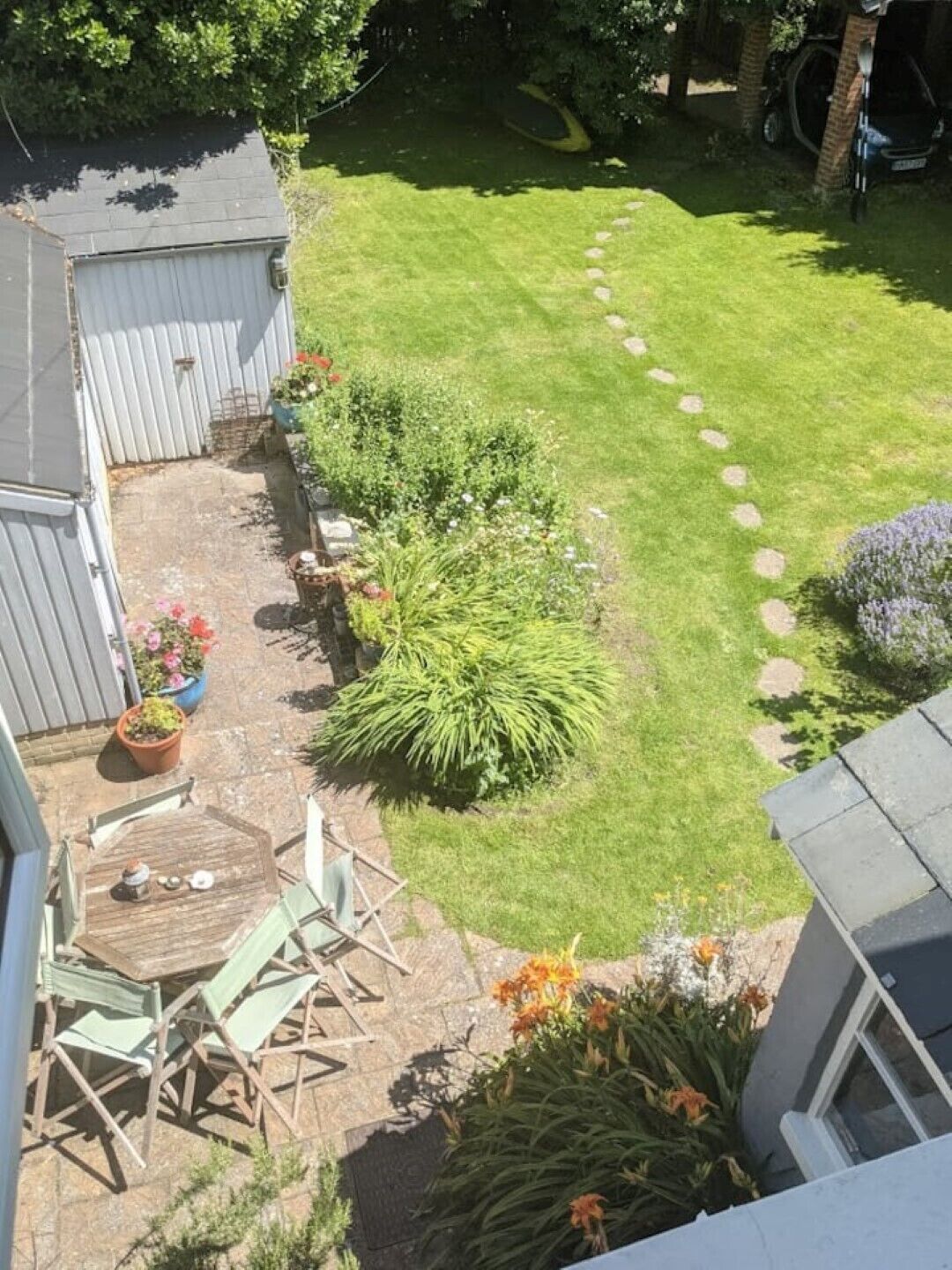 A backyard with a lawn, a wooden deck, and a shed.