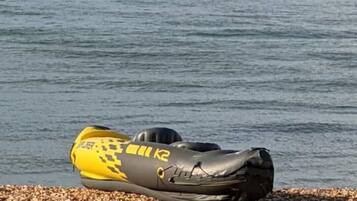 A kayak on a pebbled shore by a body of water.