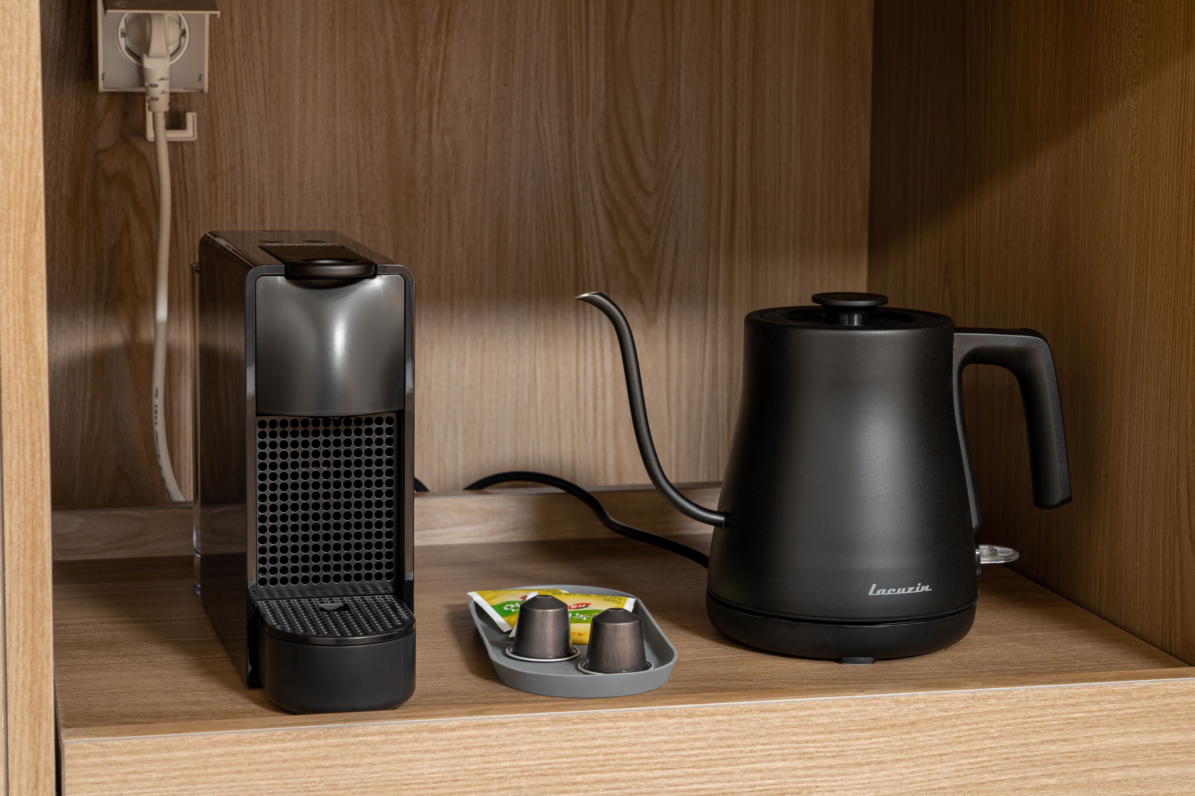 A kitchen area with a coffee maker, a kettle, and a coffee grinder on a wooden countertop.