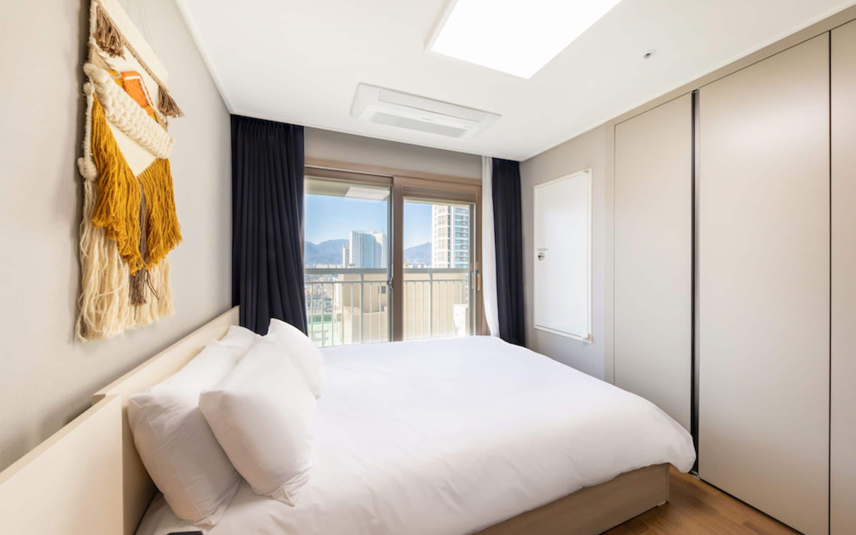 A modern hotel room with a large bed, a view of the city, and a skylight.