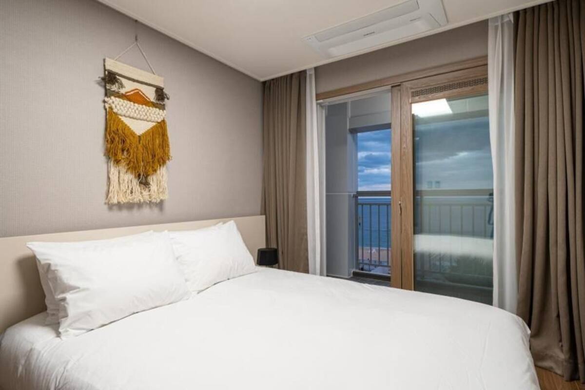 Ein Hotelzimmer mit Bett, Wandbild und Balkon mit Vorhängen.
