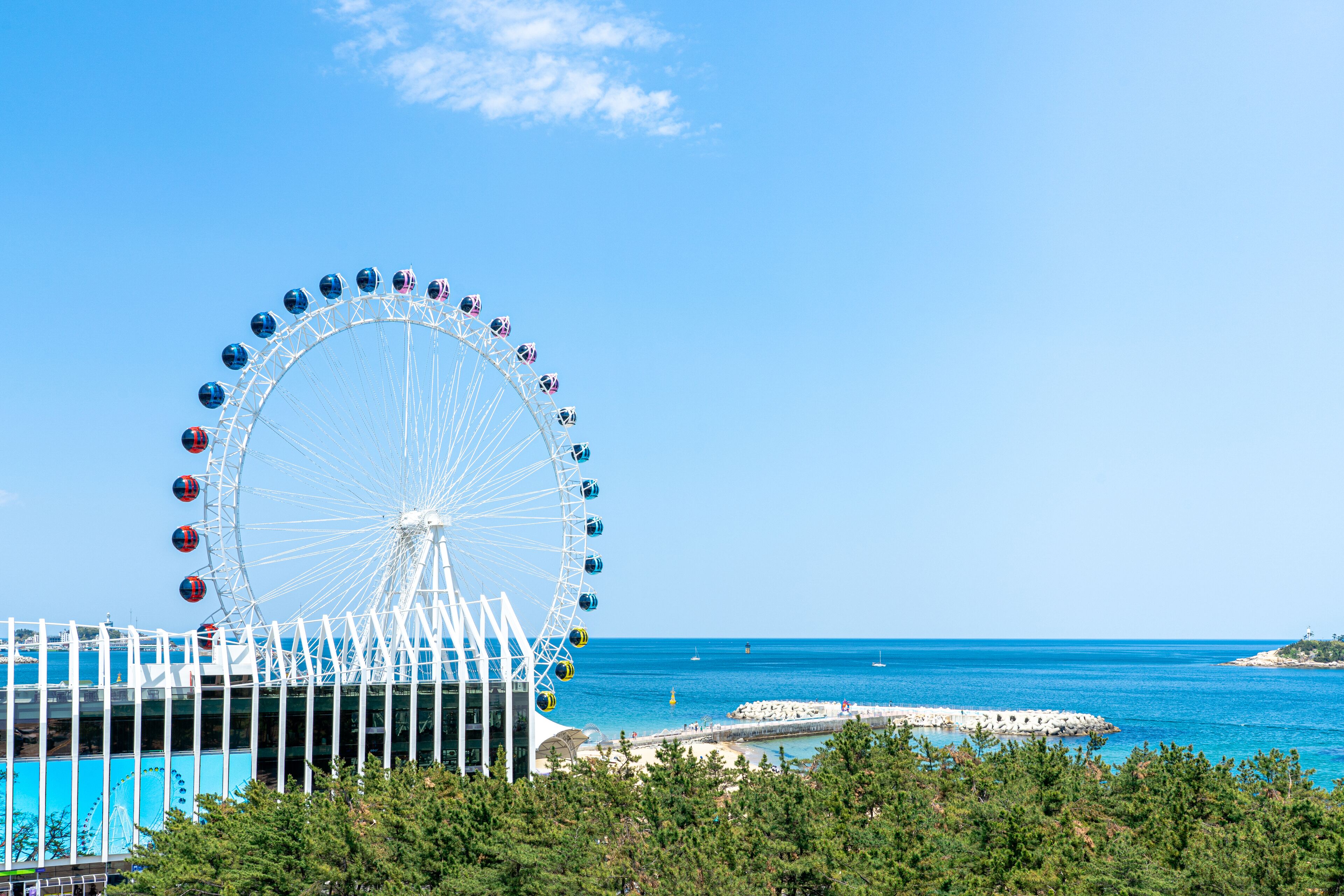 Une grande roue offrant une vue dégagée sur l’océan et, au loin, sur une côte rocheuse.