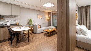 A modern living room with a sofa, a coffee table, and a dining area with a table and chairs.