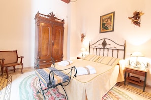 Una camera da letto ordinata con un letto, comodini, un armadio in legno e una panca.
