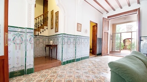 A spacious room with patterned floor tiles, a green sofa, and a staircase leading to an upper level.