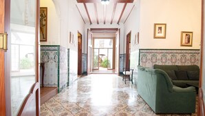 A hallway with patterned floor tiles, a green sofa, and framed pictures on the walls.