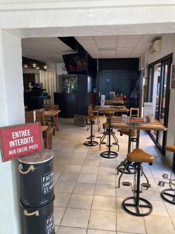 A restaurant interior with high tables and stools, a sign indicating entry is prohibited, and a barrel labeled 'FACTORY'. - Hôtel Les Pêcheurs (Banyuls-sur-Mer)