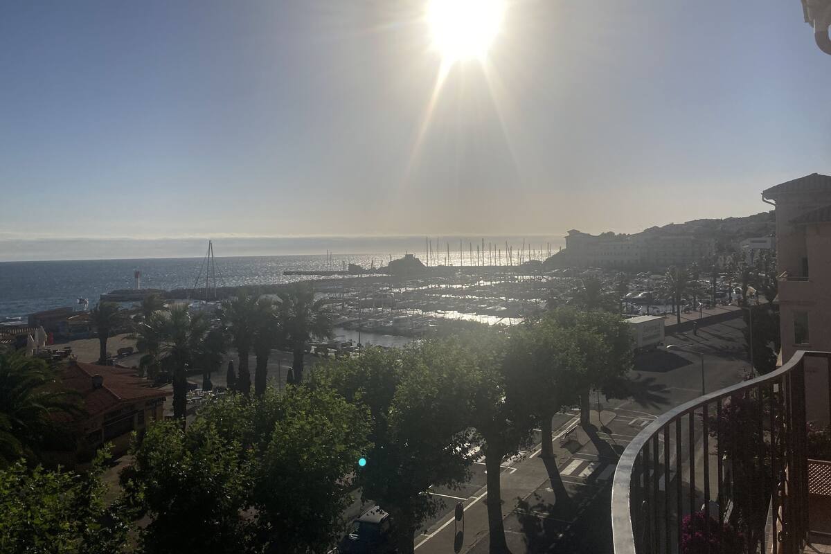 A coastal view with a marina, buildings, and a clear sky.