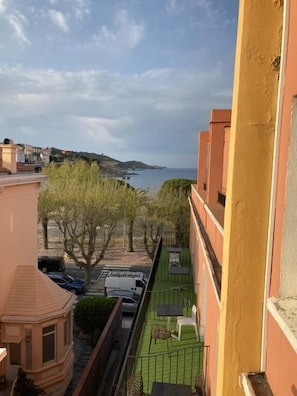 A balcony with a view of the sea, a green lawn, and neighboring buildings. - Hôtel Les Pêcheurs (Banyuls-sur-Mer)