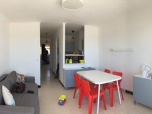 Um espaço de estar compacto com cozinha compacta, área de refeições com cadeiras vermelhas e um sofá.