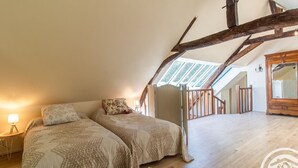 A bedroom with two beds, a wooden wardrobe, and a skylight. - Charming house with enclosed garden near the Louet river (Denée)